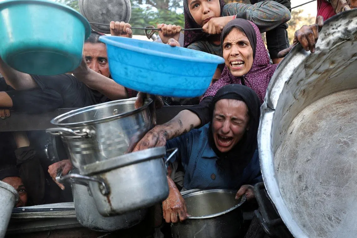 FILE PHOTO: Palestinians react as they ask for food from a charity kitchen, amid a hunger crisis, in Gaza City, July 14, 2025. REUTERS/Mahmoud Issa/File Photo