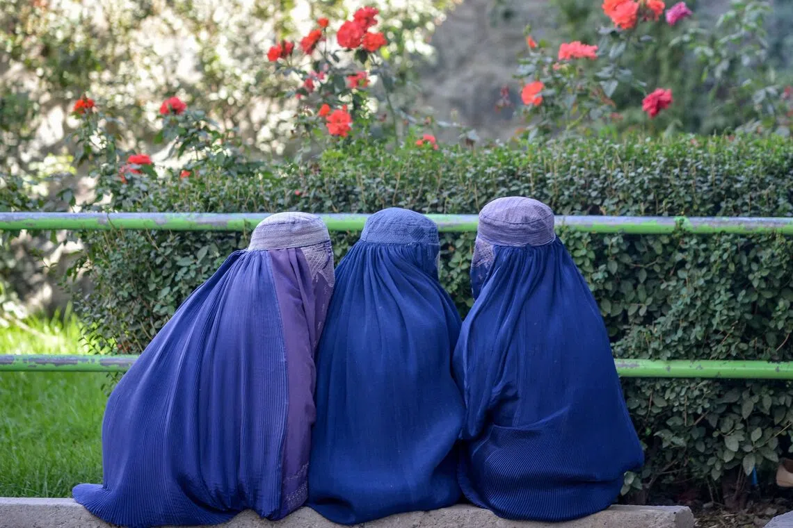 Afghan burqa-clad women sitting along a road at a market in the Faizabad district of the Badakhshan province, on Oct 9, 2025. 