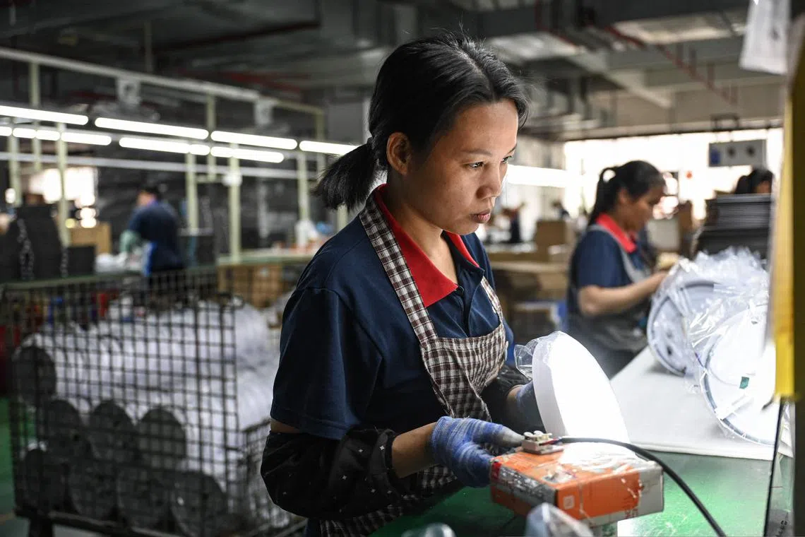 Employees work on an assembly line of lights at a factory of LED lighting manufacturer WOSEN in Zhongshan, in southern China’s Guangdong province on April 17, 2025. (Photo by JADE GAO / AFP)