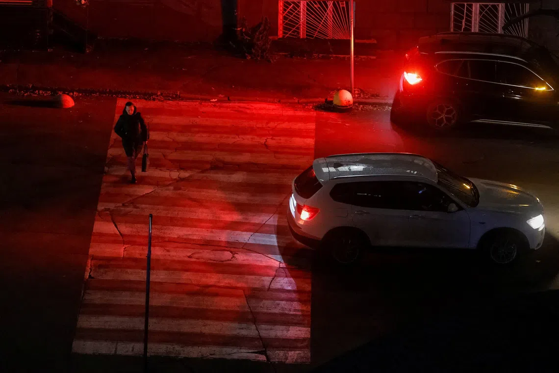 A woman crosses a street during a power blackout after critical civil infrastructure was hit by recent Russian missile and drone attacks, amid Russia's attack on Ukraine, in Kyiv, Ukraine October 14, 2025. REUTERS/Gleb Garanich