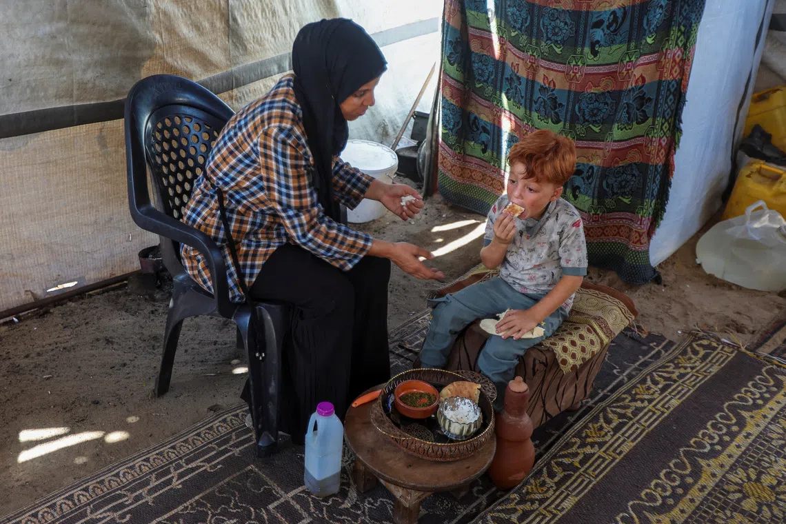 Ms Inas Abu Maamar helps feed her nephew Ahmed at their tent where they shelter after being displaced from their home, in Khan Younis. Ahmed lost his two sisters, his parents, his maternal grandparents and paternal grandfather to Israeli attacks.