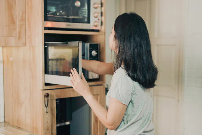 Best microwave ovens in Singapore: Woman using microwave to heat up food