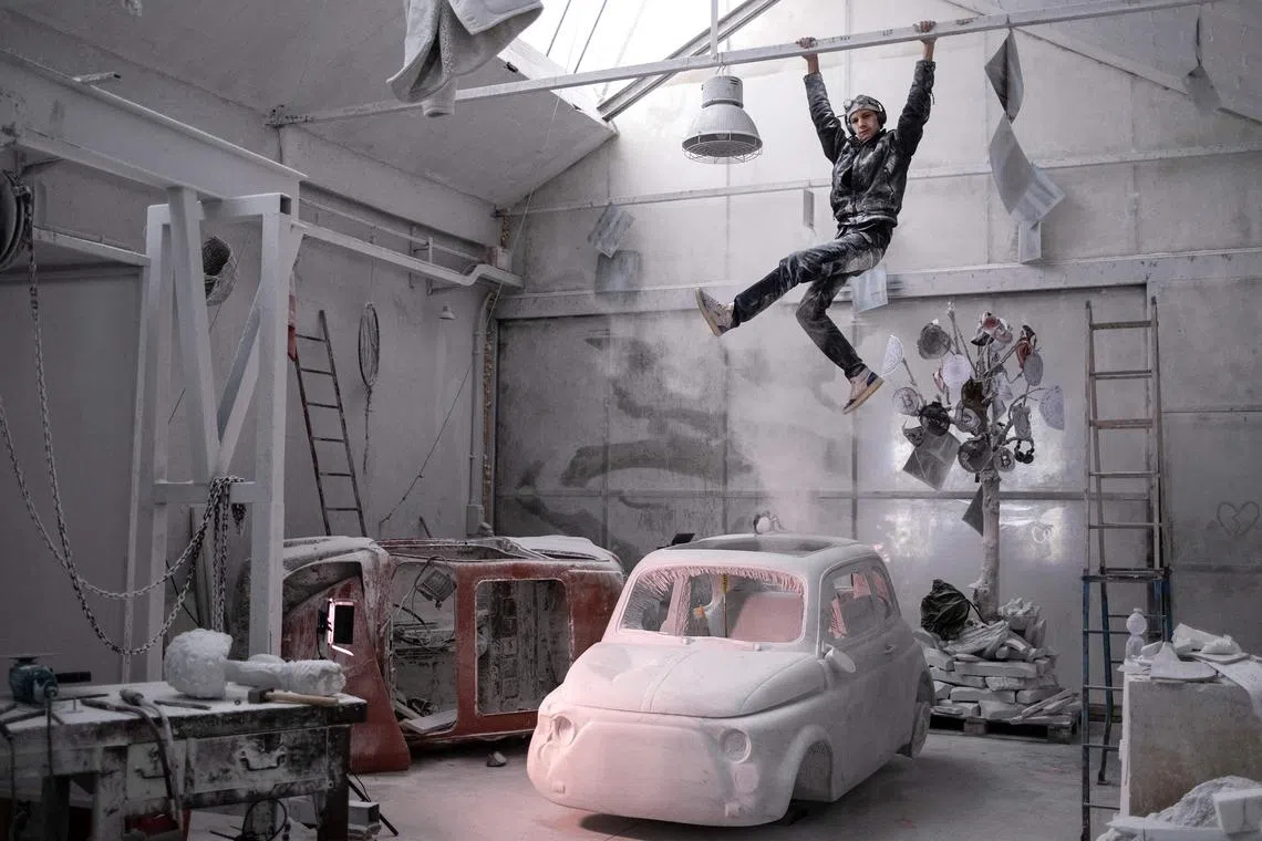 Italian artist Nazareno Biondo poses above his sculpture made from Carrara marble representing the iconic Fiat 500 car, on December 15, 2022 at his studio in Cafasse, near Turin. 