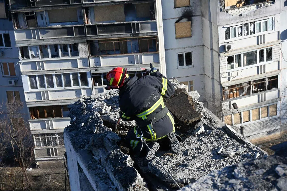 TOPSHOT - A man removes debris from a residential building during renovations of an appartment block, partially destroyed by shelling, in the outskirt of Kharkiv on January 25, 2023, amid Russian invasion of Ukraine. (Photo by SERGEY BOBOK / AFP)