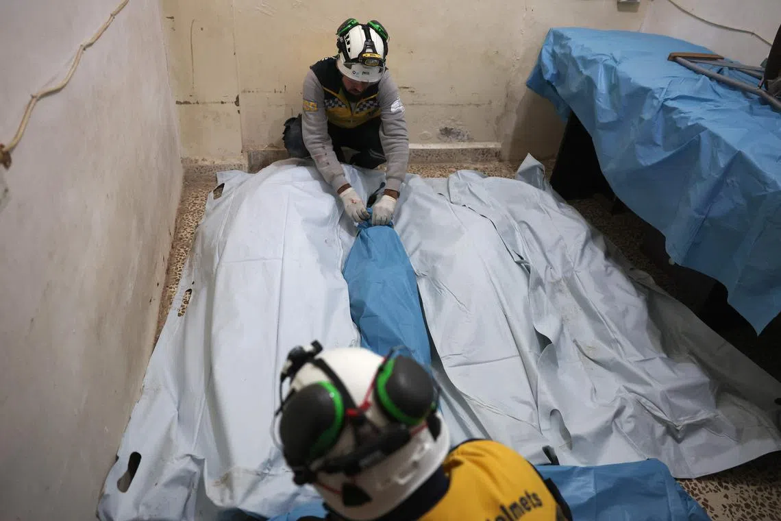 Syrian Civil Defence volunteers, known as White Helmets, gather the bodies of victims of the air strikes, from the same family, at a hospital.