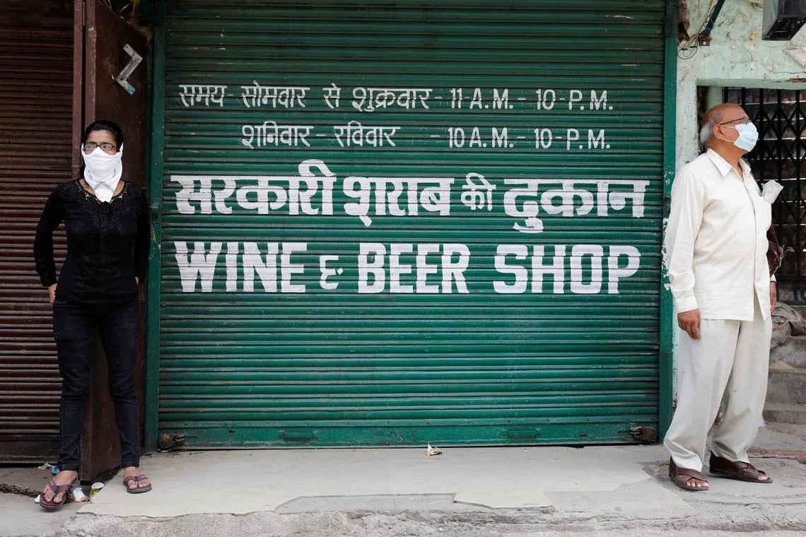 FILE PHOTO: People wearing protective masks stand outside a wine shop to buy liquor during an extended nationwide lockdown to slow the spread of the coronavirus disease (COVID-19), in New Delhi, India, May 4, 2020. REUTERS/Adnan Abidi/File Photo