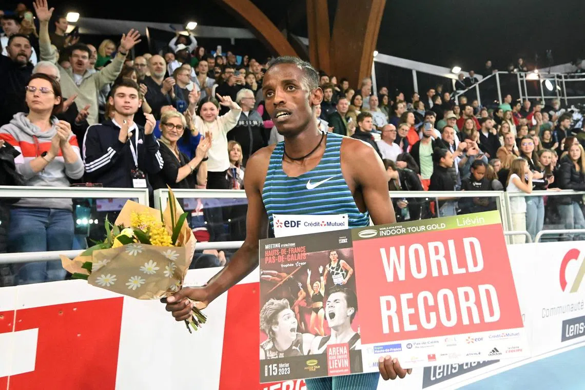 Ethiopia's Lamecha Girma holding a World Record sign as he celebrates winning the men's 3000m final race during an indoor athletics meeting in Lievin on Wednesday.