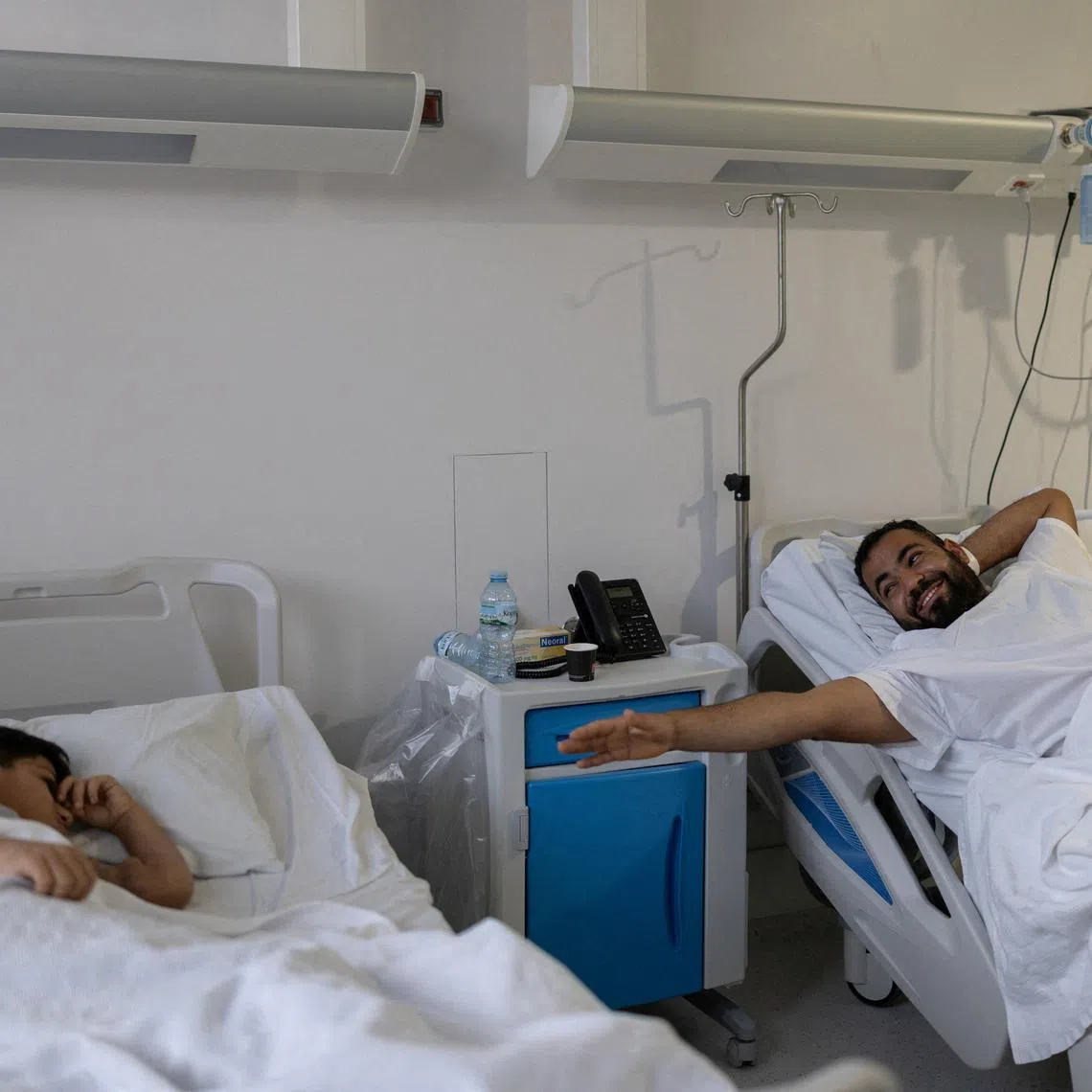 Syrian refugee Abdulaziz Aldarwish, 32, reaches out his hand towards his son Yahia Aldarwish, 10, from his hospital bed shortly before a kidney transplant in which Abdulaziz is the donor, at the Onassis National Transplant Center, in Athens, Greece, January 22, 2026. REUTERS/Stelios Misinas