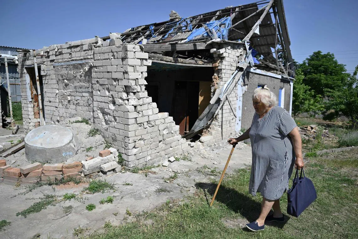 A woman walking past her house - damaged amid Russia's invasion of Ukraine - in Ukraine's Kherson region, on June 3.