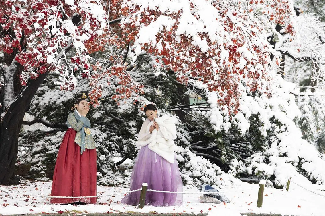 Tourists wearing Korean traditional Hanbok dresses taking pictures amid snowfall at the Gyeongbokgung Palace in Seoul, South Korea, Nov 27, 2024. 