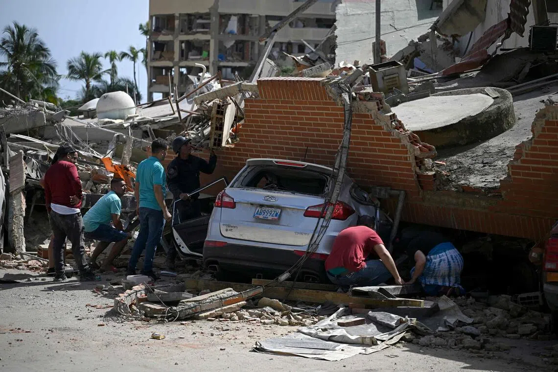TOPSHOT - People search through the rubble around a car trapped beneath the collapsed remains of a residential building following an earthquake in Catia La Mar, La Guaira state, about 30 km northwest of Caracas, on June 25, 2026. A twin earthquake that was Venezuela's largest in over a century has killed at least 164 people and destroyed multiple buildings near the capital, where residents searched on June 25 for missing relatives. (Photo by Federico PARRA / AFP)