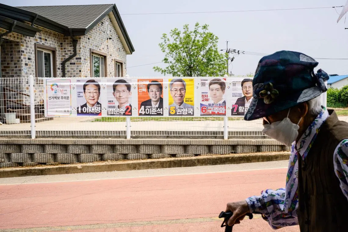 An elderly resident uses her walking stick as she walks past posters of candidates for the upcoming presidential election in Tongilchon, or Unification Village, on May 28, 2025, located some 60 kilometers from Seoul in the Civilian Control Zone (CCZ), a restricted area next to the more famous Demilitarised Zone (DMZ) that separates the two Koreas. Their village is just a stone's throw from North Korea. So whatever their political leanings, Tongilchon residents all want one thing: a South Korean president who doesn't stoke tensions with Pyongyang. (Photo by ANTHONY WALLACE / AFP) / TO GO WITH: SKorea-NKorea-politics-vote, by Roland de Courson and Minji Suh