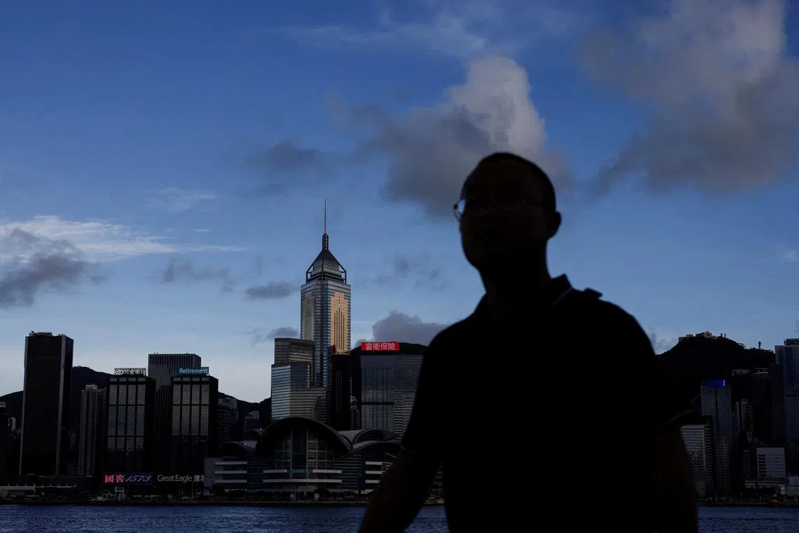 FILE PHOTO: A man walks along the waterfront in front of Victoria Harbour, with the iconic skyline buildings as a backdrop, in Hong Kong, China June 28, 2023. REUTERS/Tyrone Siu/File Photo