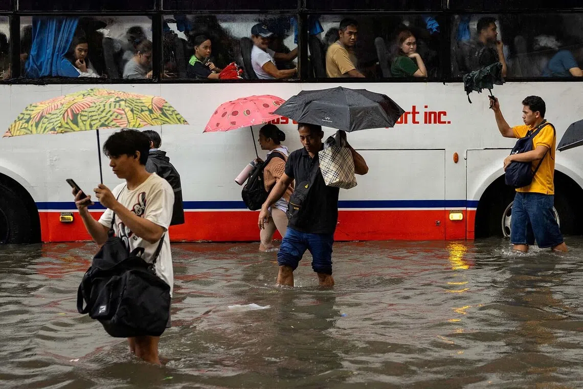People wade through floodwaters while passengers on a bus look on during heavy monsoon rains in Manila City, Philippines, August 17, 2026. REUTERS/Eloisa Lopez TPX IMAGES OF THE DAY