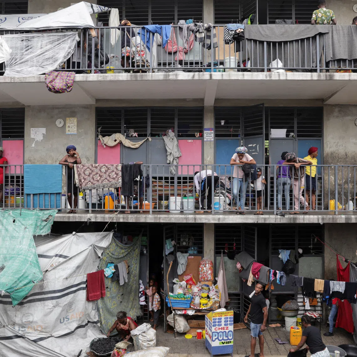 FILE PHOTO: People stand on balconies at the Ecole Nationale Argentine Bellegarde, a school turned into a shelter for some of the more than 1.3 million Haitians who have been internally displaced due to gang violence, in Port-au-Prince, Haiti, October 27, 2025. REUTERS/Patrice Noel/File Photo