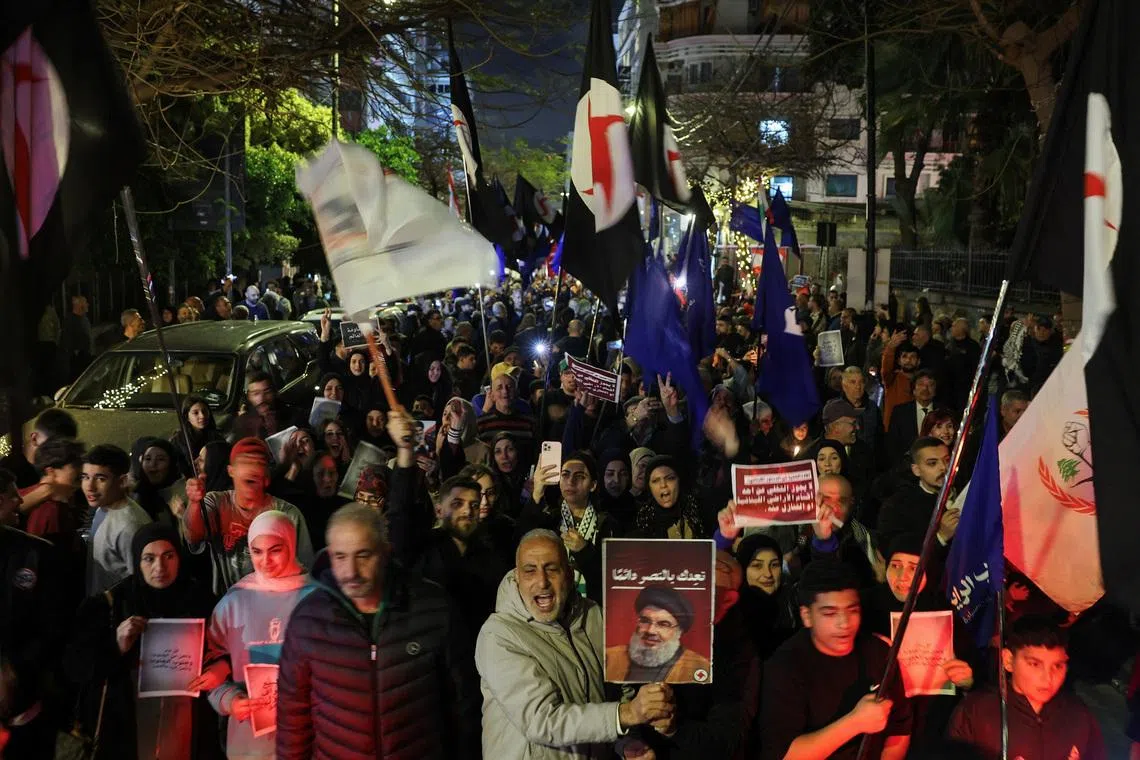 A person raising a portrait of late Hezbollah leader Hassan Nasrallah during a demonstration in support of Hezbollah and Iran in Beirut on March 27.