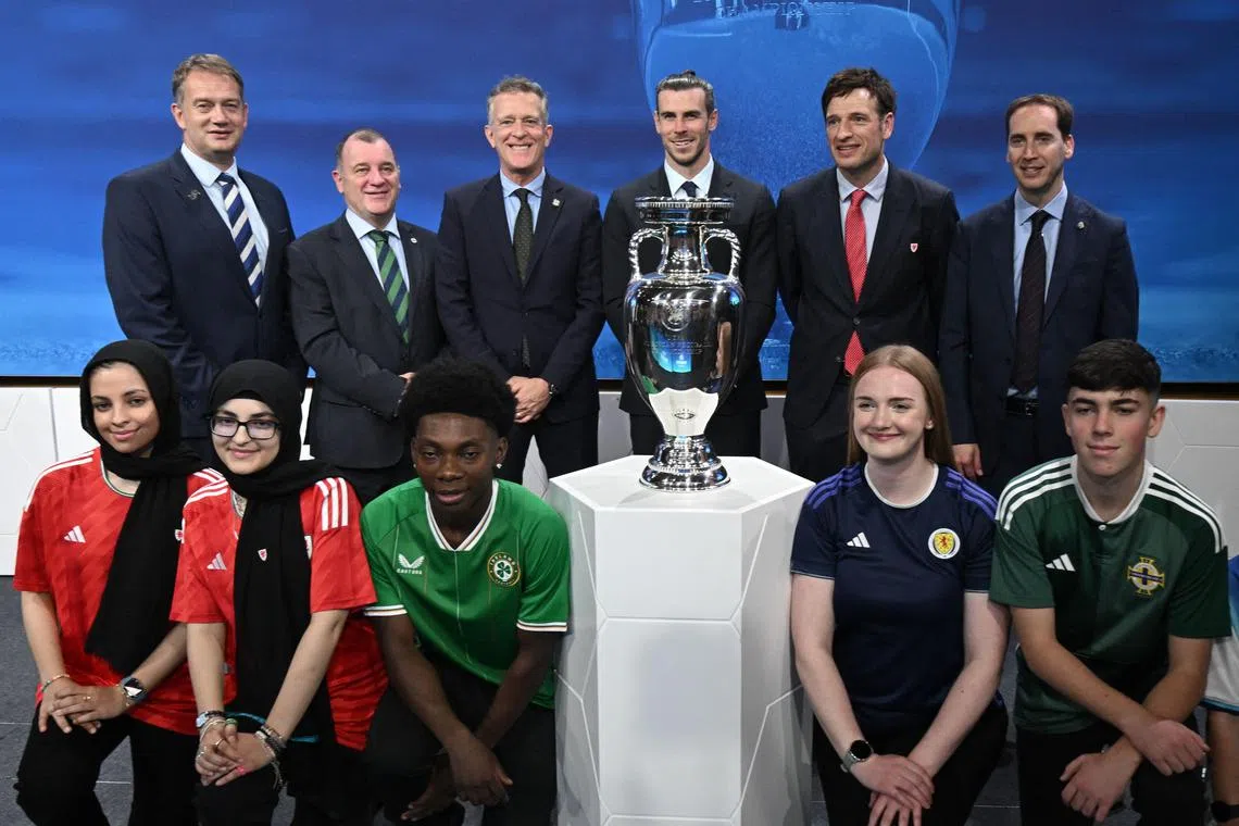 From left: Scottish Football Association CEO Ian Maxwell, Northern Ireland Football Association CEO Patrick Nelson, Football Association of Ireland CEO Jonathan Hill, Welsh retired professional footballer, heading the delegation of UK and Ireland Gareth Bale, Welsh Football Association CEO Noel Mooney and Football Association CEO English Mark Bullingham posing with fans next to the trophy after United Kingdom and Ireland were elected to host the Euro 2028 fooball tournament during the announcement ceremony at the Uefa headquarters in Nyon on Tuesday.