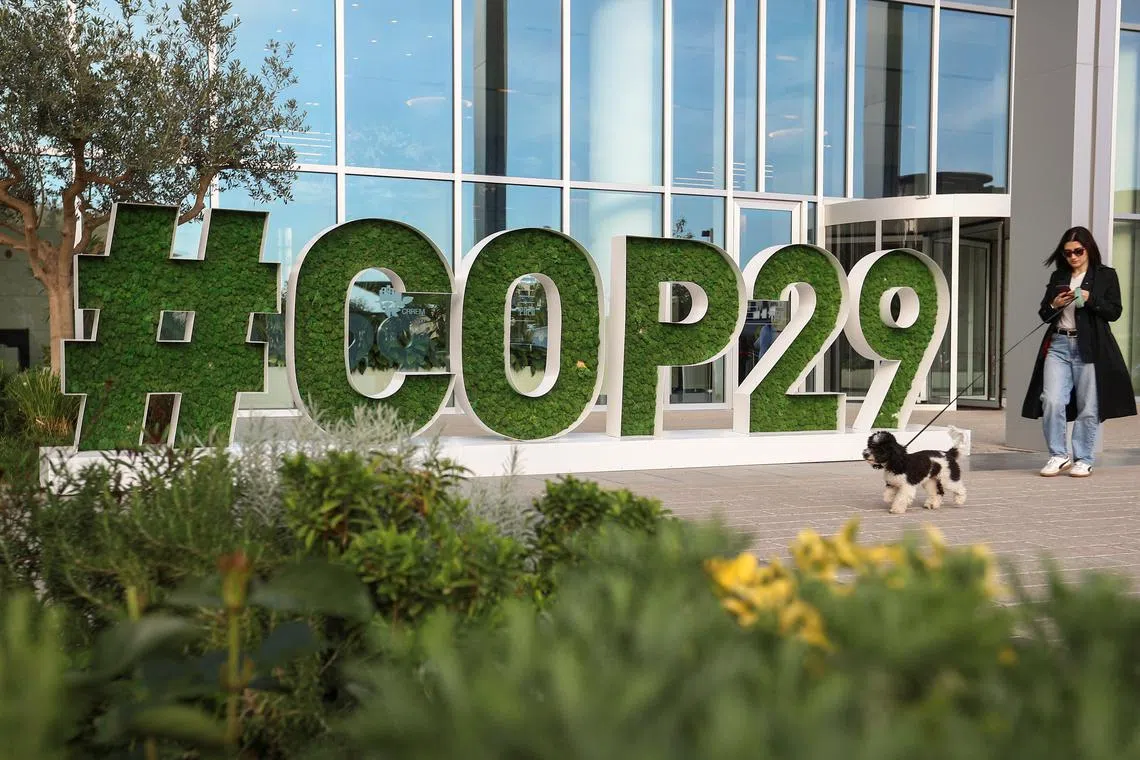 FILE PHOTO: A woman walks past a sign of the COP29 United Nations Climate Change Conference, in Baku, Azerbaijan October 31, 2024. REUTERS/Aziz Karimov/File Photo