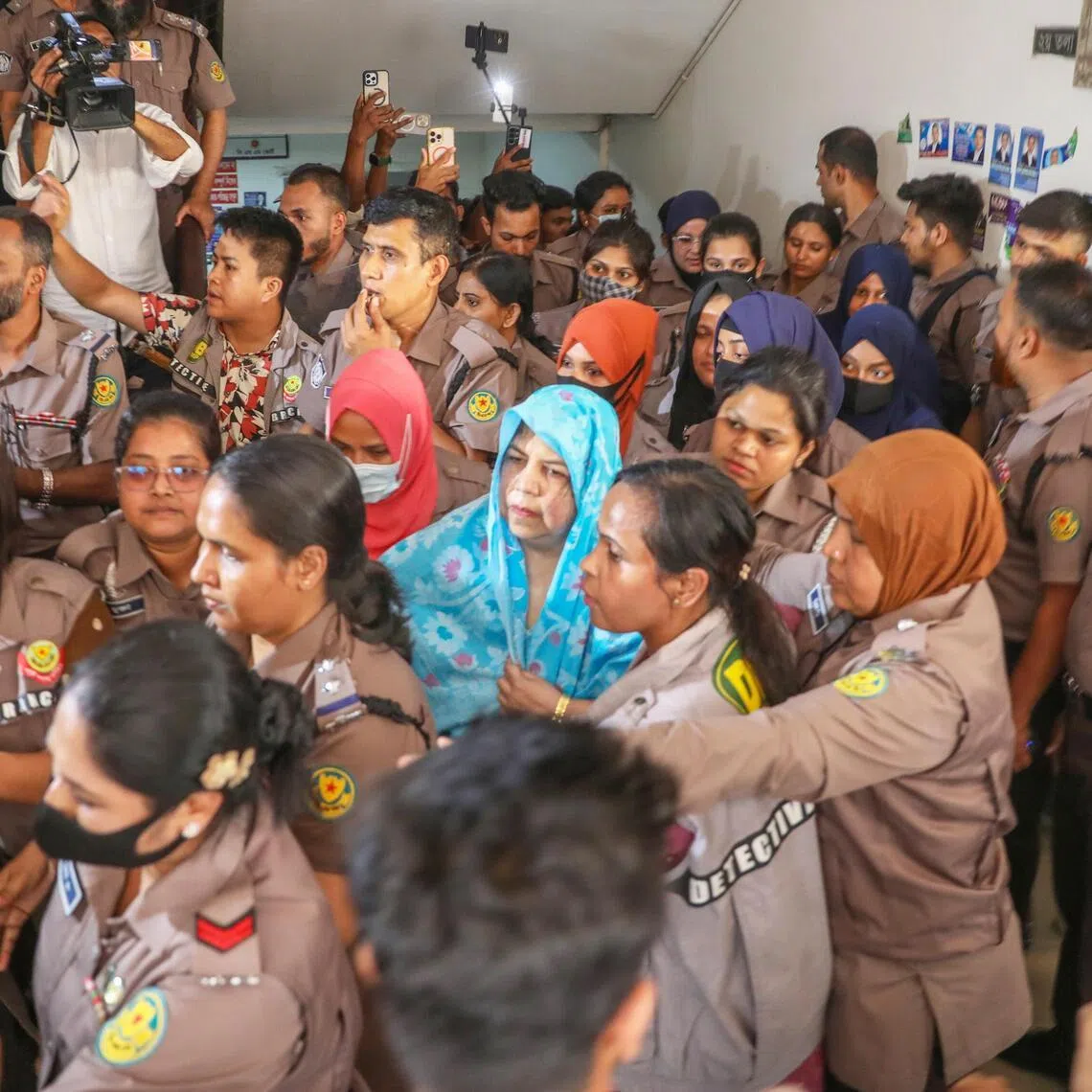 Bangladesh police officers stand guard as former speaker Shirin Sharmain Chowdhury (centre) is escorted to the Chief Metropolitan Magistrate (CMM) Court in Dhaka, Bangladesh on April 7, 2026. 