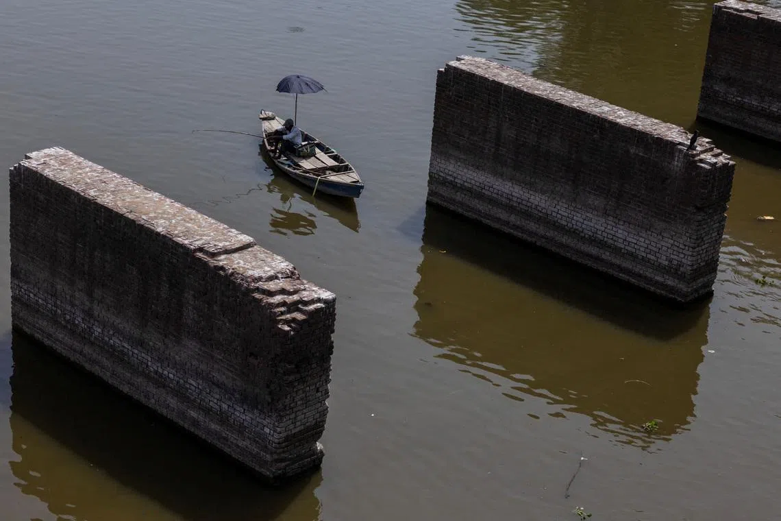 FILE PHOTO: A man catches fish as sits in his boat in the river Yamuna on a hot summer day in New Delhi, India, June 11, 2026. REUTERS/Adnan Abidi/File Photo