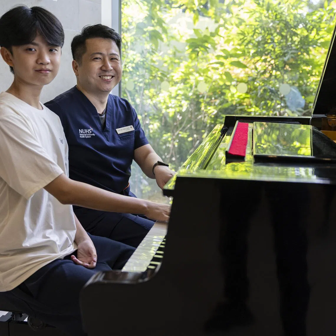 Ryan Lim (left) from Ahmad Ibrahim Secondary School, and his doctor Dr Lee Yang Yang playing the piano at the NUHS Tower Block on Aug 25.