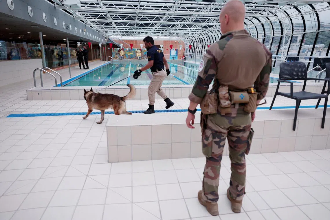 FILE PHOTO: Paris 2024 Olympics - Paris, France - July 21, 2024 A police officer and a sniffer dog inspect a swimming pool area ahead of the Olympics REUTERS/Gonzalo Fuentes/File Photo