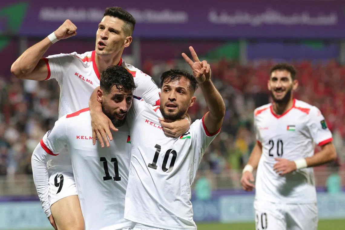Palestinian forward Oday Dabbagh celebrates with teammates after scoring their third goal.