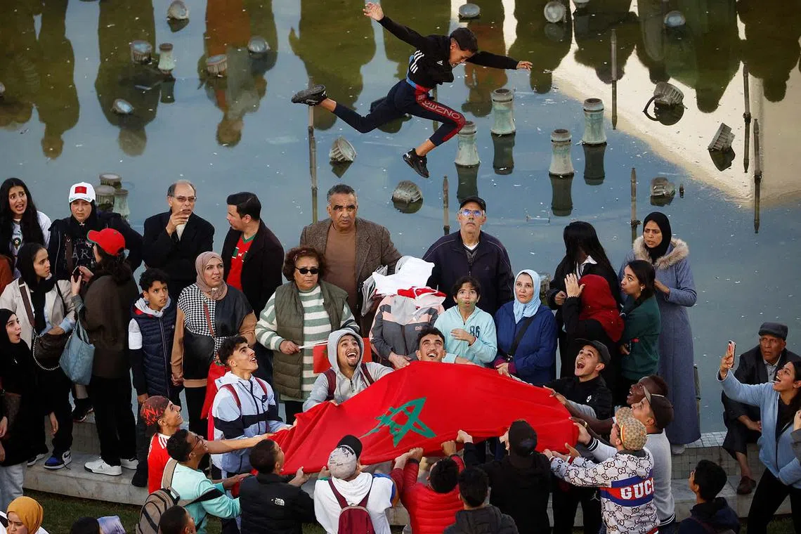 A young fan is thrown in the air using a Morocco flag before the arrival of the Morocco team in Rabat, Morocco, Dec 20, 2022, after playing the World Cup in Qatar.