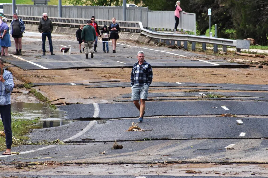 People inspect the damaged road following flooding in the town of Canowindra, in the Central West region of New South Wales, Australia, Nov 15, 2022. 