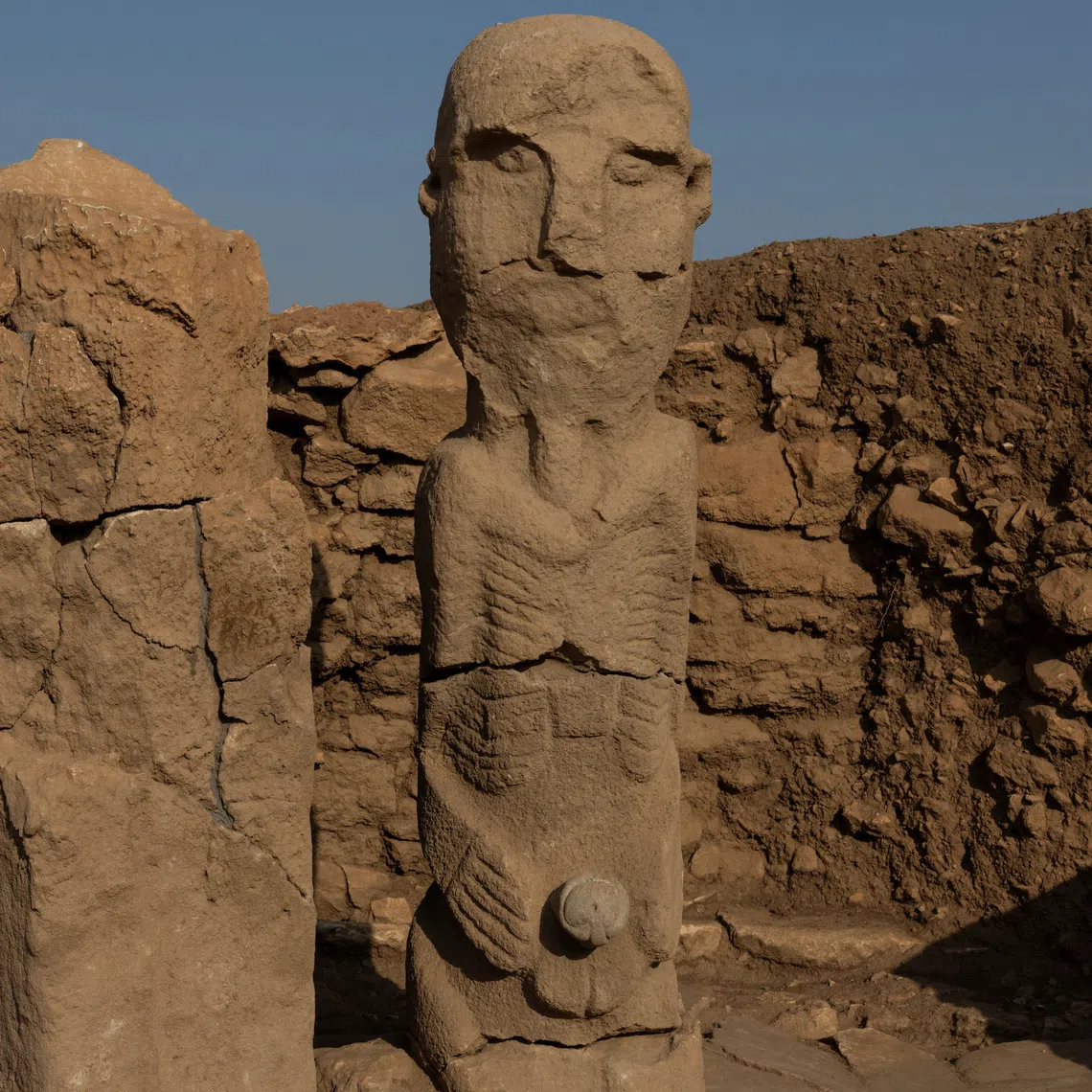 A pillar and a human statue stand at the Karahantepe excavation site, widely regarded with Gobeklitepe as keys to understanding the birth of symbolic thought, social complexity and monumental architecture thousands of years before cities or states existed, near the southeastern city of Sanliurfa, Turkey, November 25, 2025. REUTERS/Umit Bektas