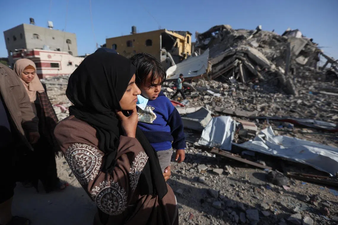 A Palestinian carries her child as she walks towards her her home in Khan Younis town in southern Gaza.