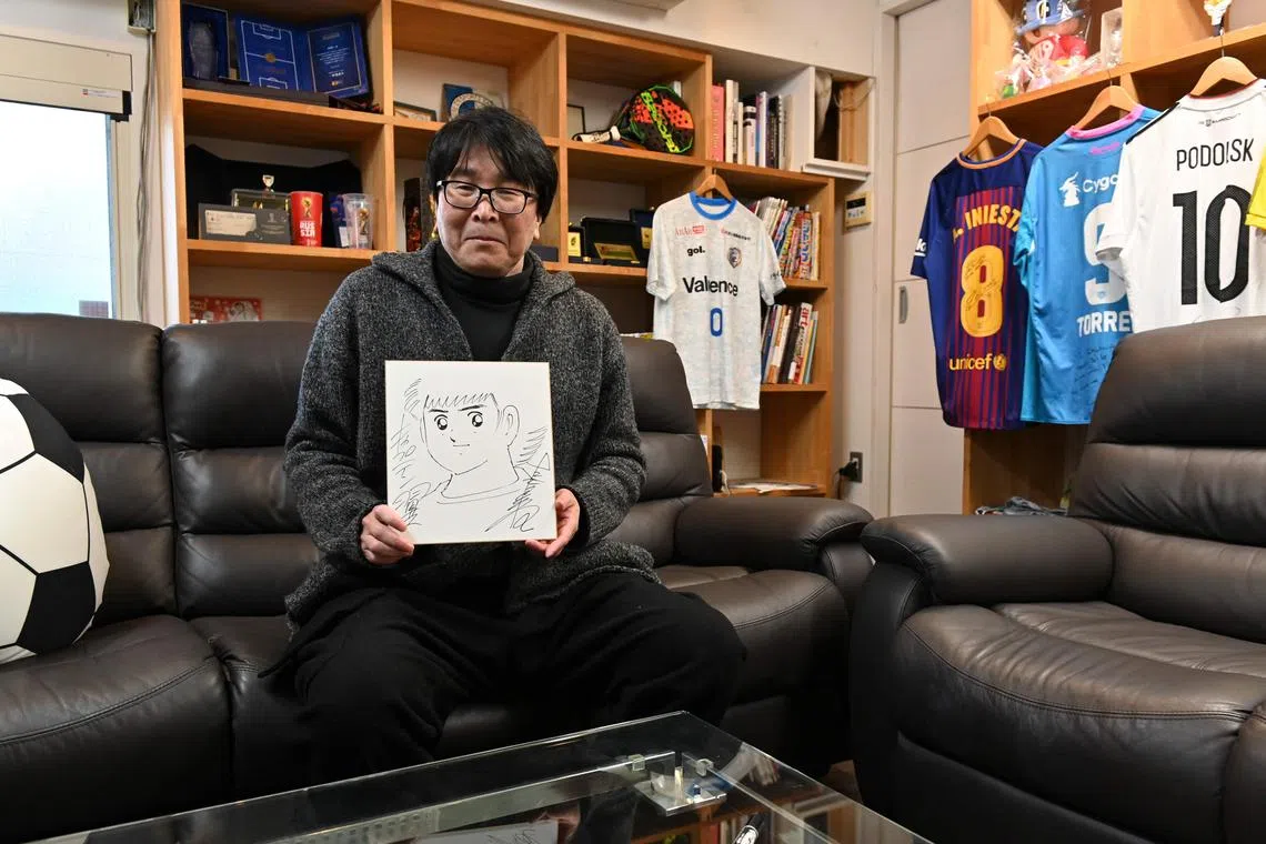 This photo taken on January 30, 2023 shows Japanese cartoonist and manga artist Yoichi Takahashi, best known for his work "Captain Tsubasa", displaying his autograph with the painting of the main character following an interview with AFP at his workplace in Tokyo. (Photo by Kazuhiro NOGI / AFP) / TO GO WITH: Japan-cartoon-fbl-Tsubasa-animation, INTERVIEW by Andrew MCKIRDY