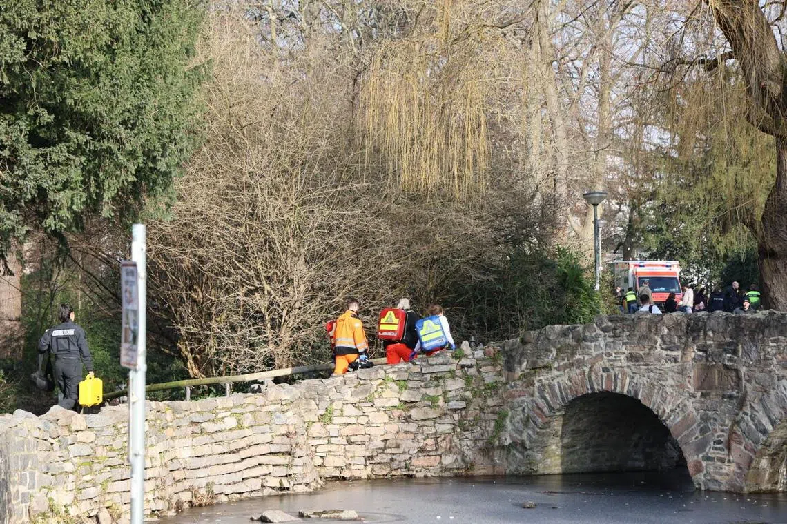 Rescue workers and forensic technicians walk up a small bridge near the site of a stabbing in Aschaffenburg on Jan 22, 2025. 