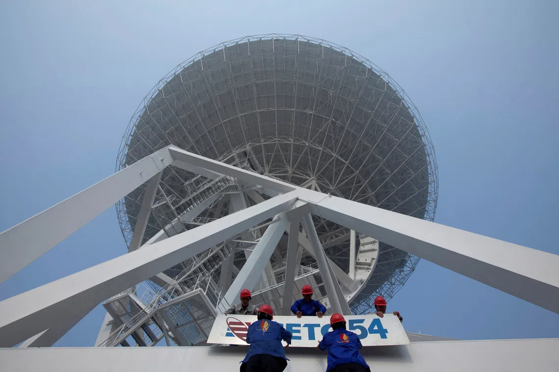 FILE PHOTO: Employees install a signage of the 54th Research Institute of CETC (China Electronic Technology Group Corporation), which takes the main responsibility of the research and development tasks of a massive radio telescope, at the foot of the telescope in Shanghai October 28, 2012. The telescope for use in space observation and was unveiled Sunday at the foot of Sheshan Mountain in Shanghai, Xinhua News Agency reported. The telescope stands at more than 70 metres (230 ft) and weighs 2,650 tonnes, according to local media. Picture taken October 28, 2012. REUTERS/Stringer (CHINA - Tags: SOCIETY SCIENCE TECHNOLOGY) CHINA OUT. NO COMMERCIAL OR EDITORIAL SALES IN CHINA/File Photo