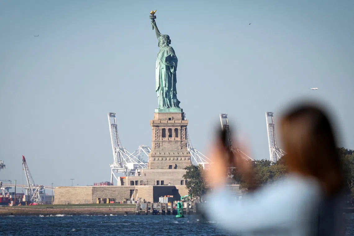 A woman photographs the Statue of Liberty from Battery Park during the first day of a partial US government shutdown in New York City, on Oct 1.