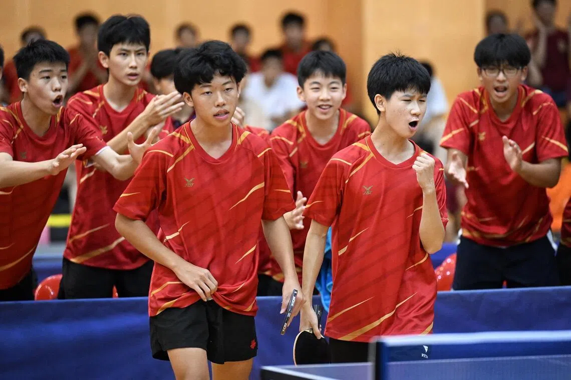 Hwa Chong Institution paddlers Rayner Young (left) and John Ang are cheered on by their team mates during their match against Raffles Institution in the B Division Boys table tennis final on April 9.
