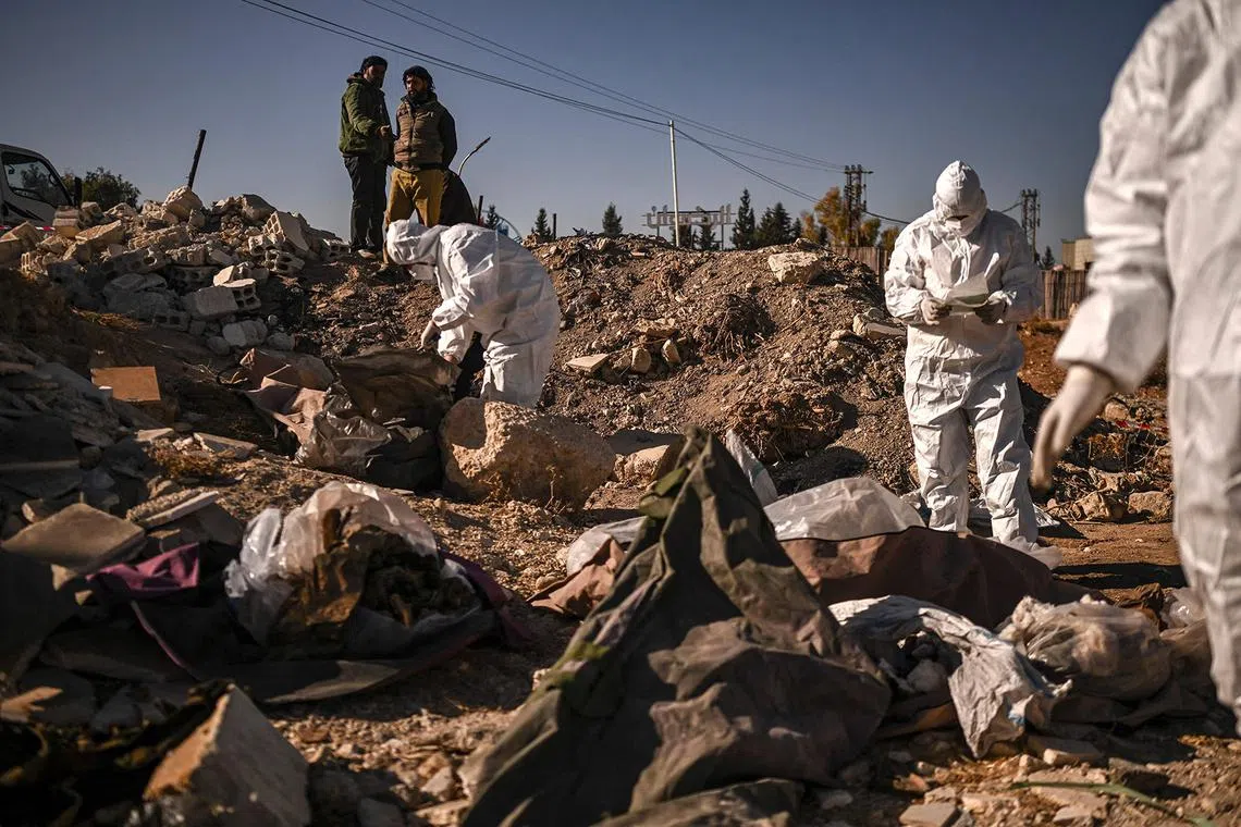 TOPSHOT - Members of Syria's White Helmets civil defence collect human remains at a mass grave that was uncovered, in Damascus, on December 16, 2024. Islamist-led rebels took Damascus in a lightning offensive on December 8, ousting president Bashar al-Assad and ending five decades of Baath rule in Syria. According to the Syrian Observatory for Human Rights, more than 100,000 people died in Syria's jails and detention centres from 2011. (Photo by Aris MESSINIS / AFP)