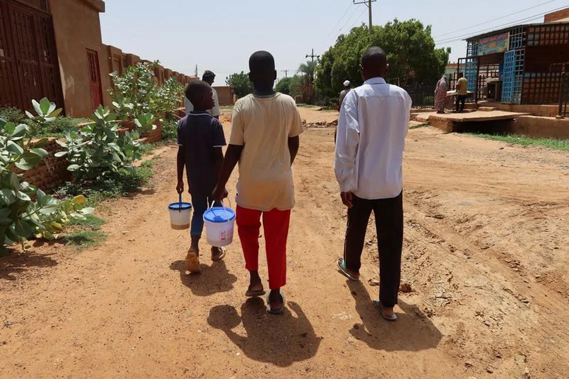 People hold containers filled with food distributed by volunteers in Omdurman, Sudan, September 3, 2023. REUTERS/El Tayeb Siddig/File Photo