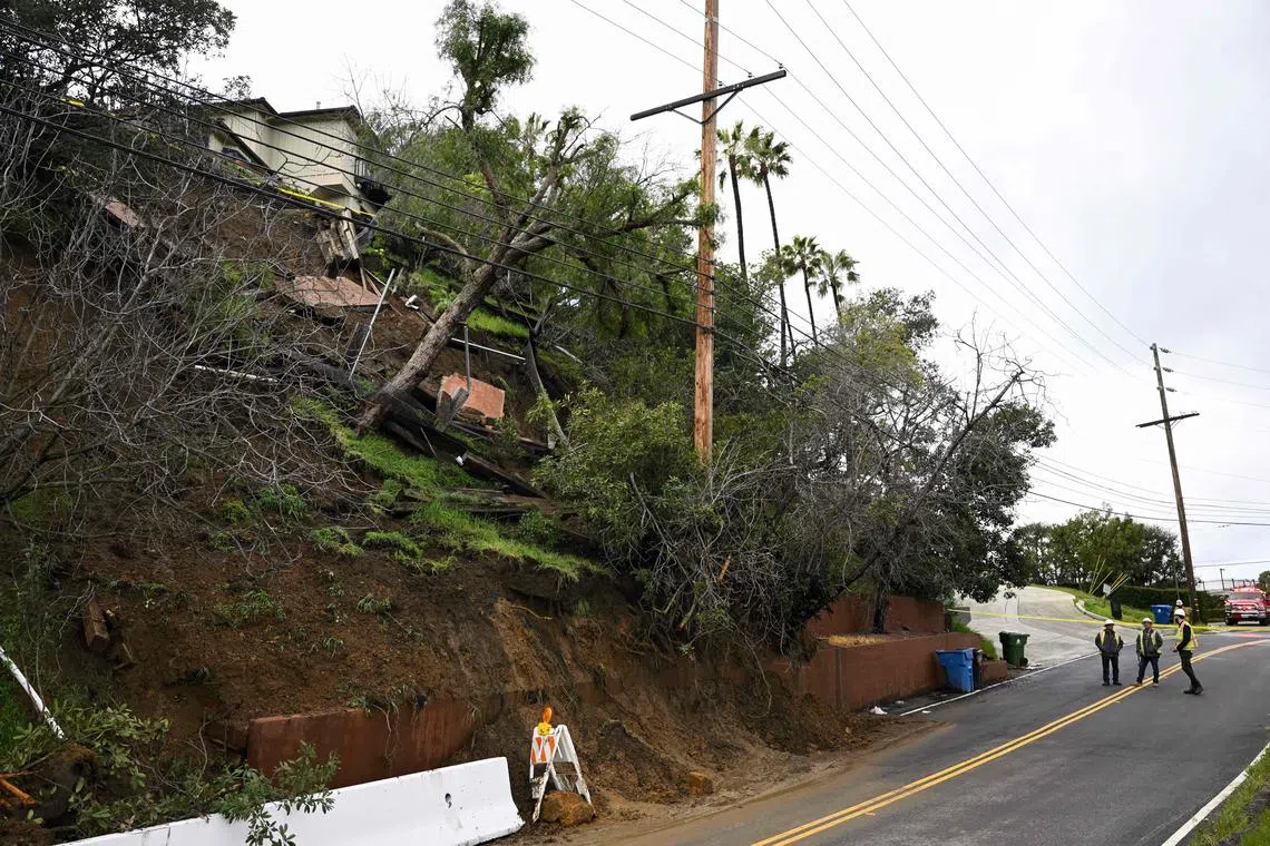 A public works crew looks at the damaged hillside from mud flows and a landslide below a home above Mulholland Drive following heavy rain from winter storms on February 28, 2023 in Los Angeles, California. (Photo by Patrick T. Fallon / AFP)