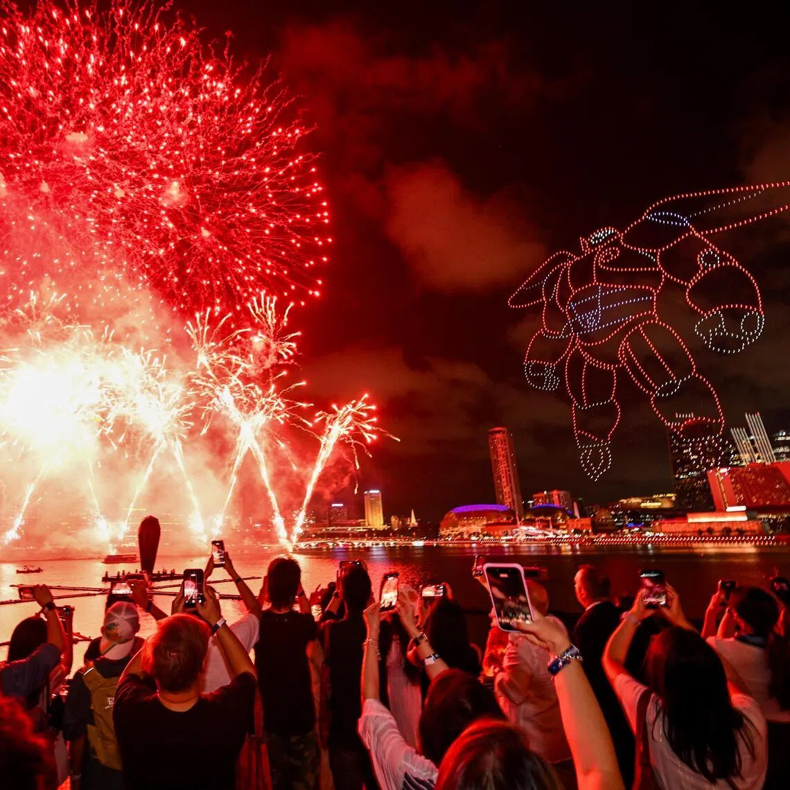 People watching a drone and firework show featuring Disney character Baymax at the Marina Bay area on March 13, 2026.