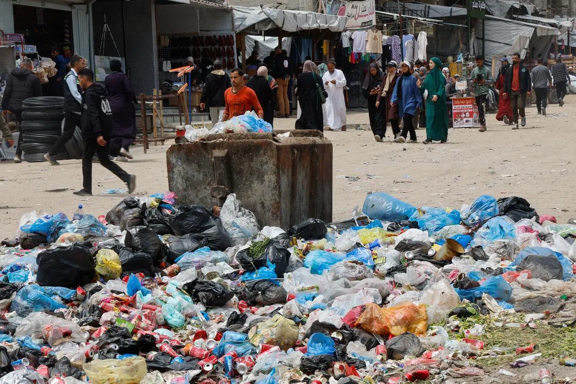 Palestinians walk past piles of garbage and waste near tents for displaced people, amid the spread of rodents, in Khan Younis in the southern Gaza Strip, April 27, 2026. REUTERS/Haseeb Alwazeer