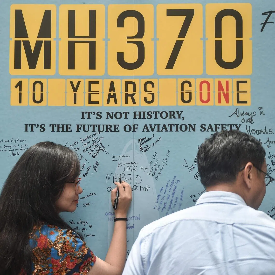 A March 2024 photo shows a woman writing a message to mark the 10th year since Malaysia Airlines flight MH370 carrying 239 people disappeared from radar screens while en route from Kuala Lumpur to Beijing.