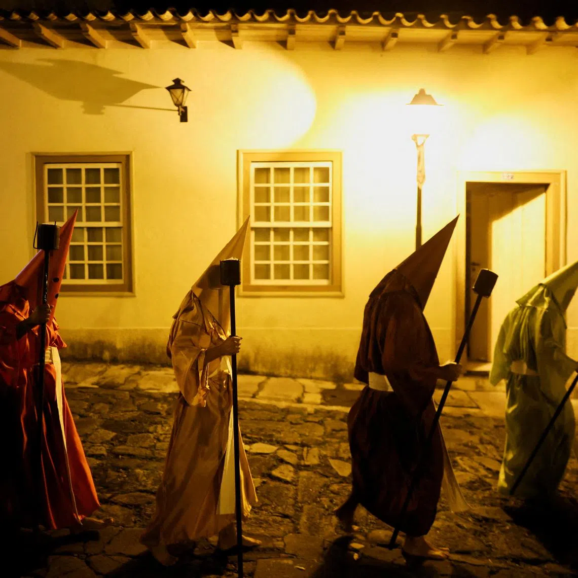 FILE PHOTO: Hooded Catholic faithful walk in the Torch Procession, known as Fogareu, during the Holy Week in Goias, State of Goias, Brazil April 16, 2025. REUTERS/Adriano Machado/File Photo