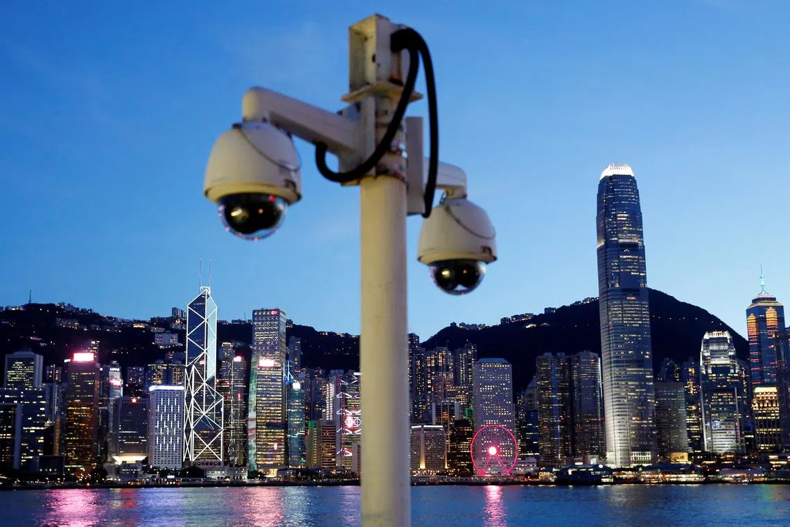 A pair of surveillance cameras are seen along the Tsim Sha Tsui waterfront as skyline buildings stand across Victoria Harbor in Hong Kong, China July 28, 2020. REUTERS/Tyrone Siu