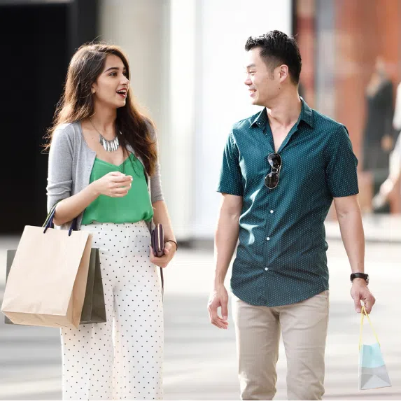 Indian woman and Chinese man holding shopping bags and shopping along Orchard Road