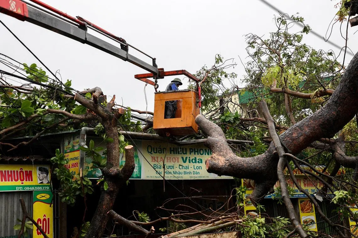 A worker removing a fallen tree from a local shop after Typhoon Bualoi makes landfall in Nghe An province, Vietnam, on Sept 29, 2025.  