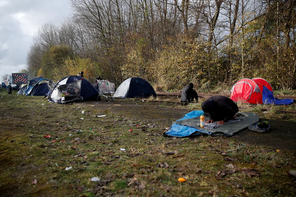 FILE PHOTO: A migrant prays at a makeshift migrant camp in Loon Beach, the day after 27 migrants died when their dinghy deflated as they attempted to cross the English Channel, in Dunkerque near Calais, France, November 25, 2021. REUTERS/Johanna Geron/File Photo