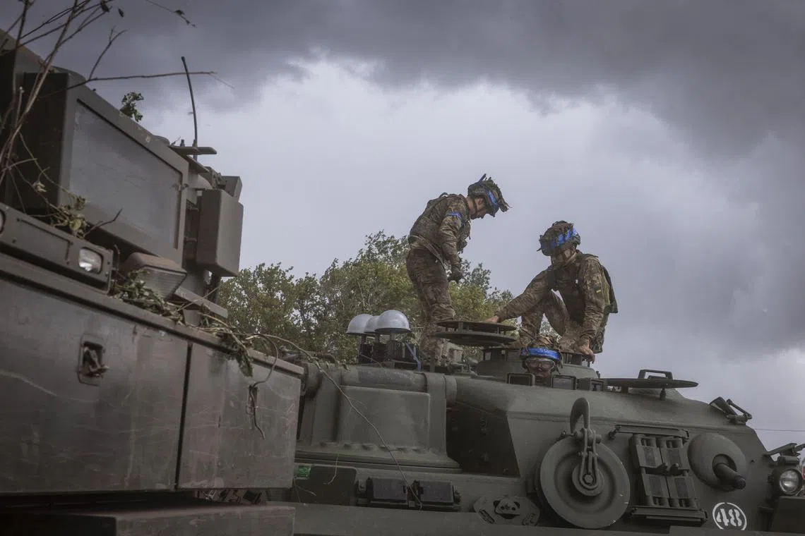 Ukrainian soldiers climbing out of an armoured vehicle on a road near the Russian border, in the Sumy region of Ukraine.
