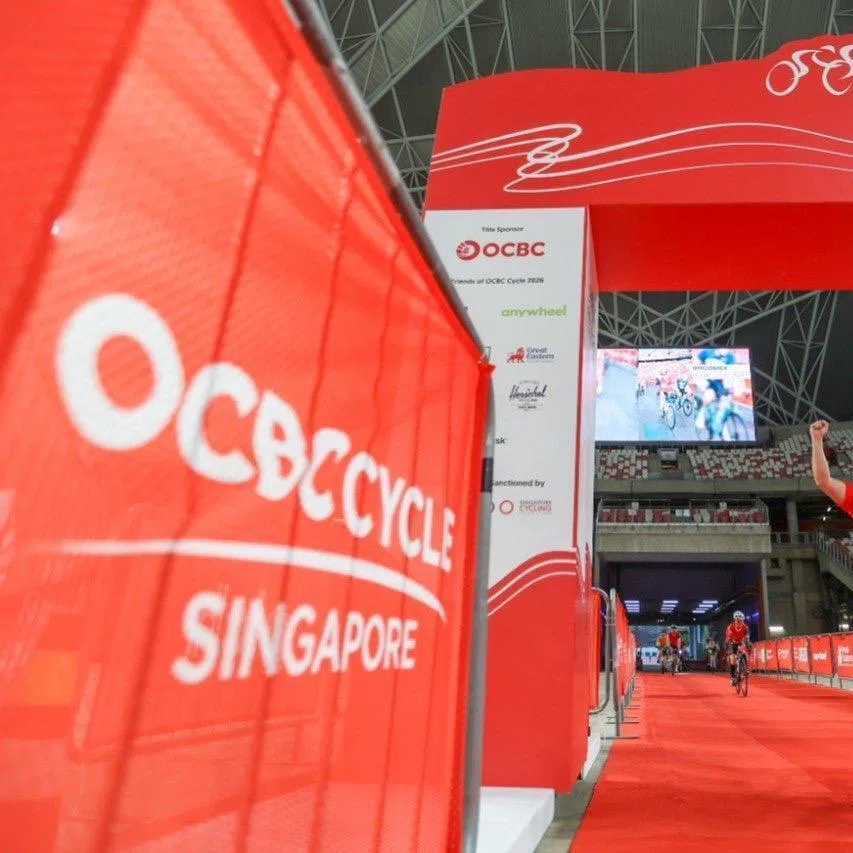 A cyclist raising his arms in celebration as he crosses the OCBC Cycle finishing line at The Kallang on May 10, 2026.