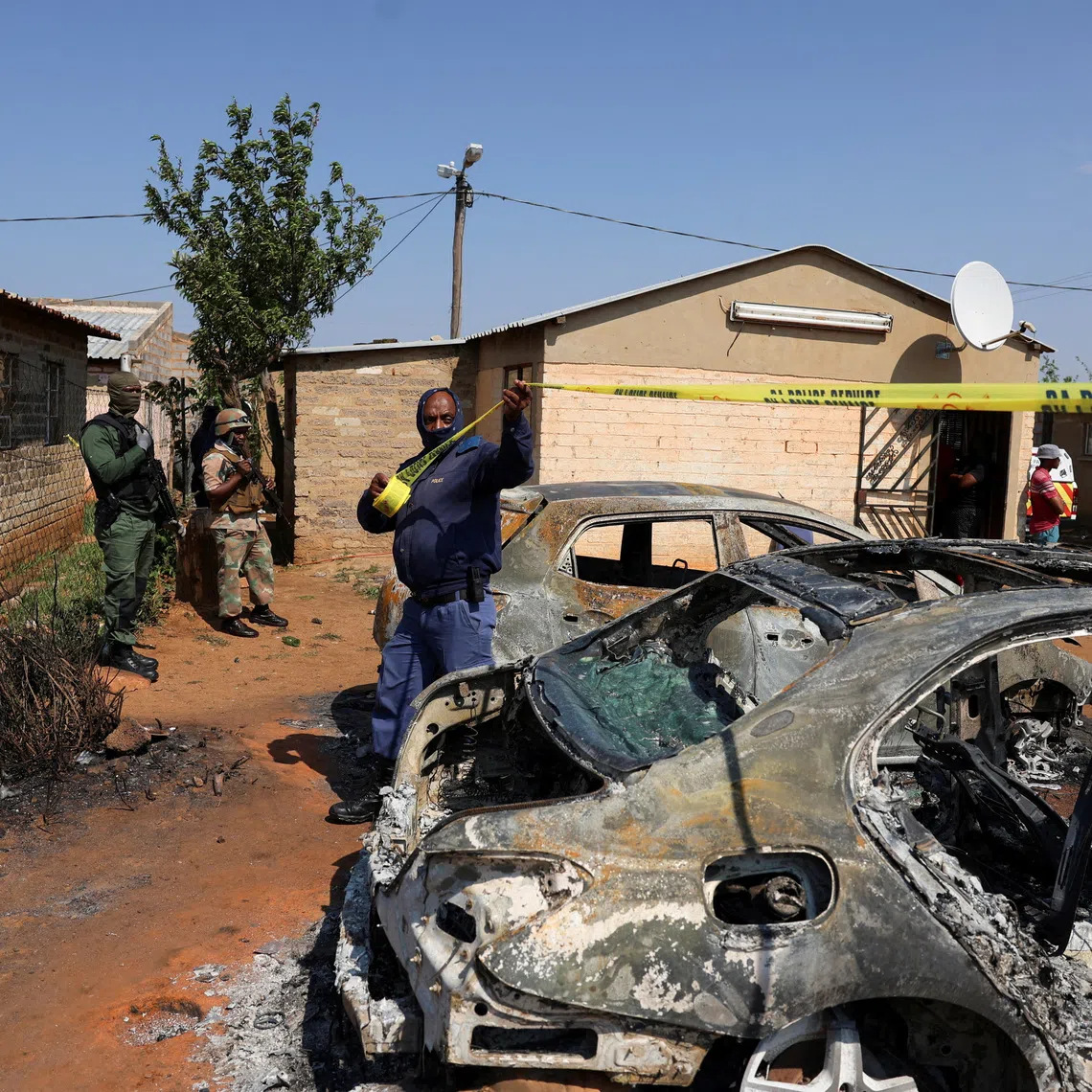 Emergency personnel cordon off an area next to burnt vehicles at the site of a deadly shooting at a tavern in Wedela township, southwest of Johannesburg, South Africa, September 27, 2026. REUTERS/Oupa Nkosi